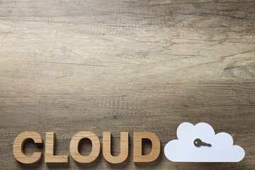 White, paper cloud with a key and the word "cloud" on a wooden background, place for text
