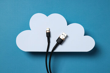 White, paper cloud with a black USB cable on a blue background