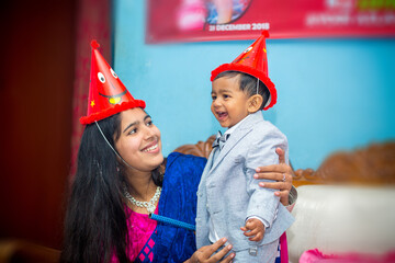 Asian mother and her little boy baby celebrating a birthday. Happy Smiling moment of a mother and boy wearing birthday hats.