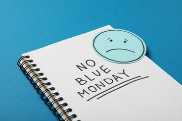 Notepad with text No Blue Monday and sad emoji on blue background, close up