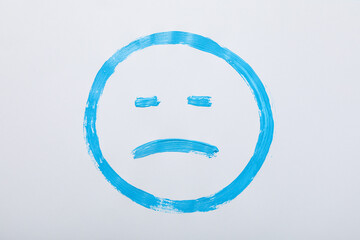 Blue sad emoji on white background, top view