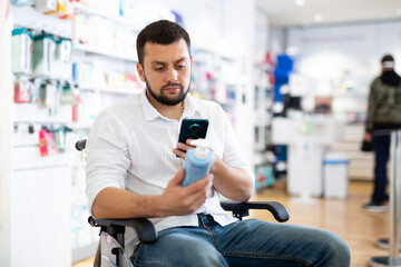 Male customer in wheelchair scans the barcode on a medicine bottle with his smartphone