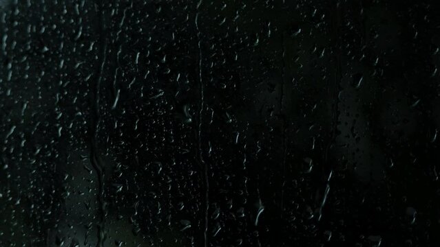 Raindrops running down the glass, dark background.