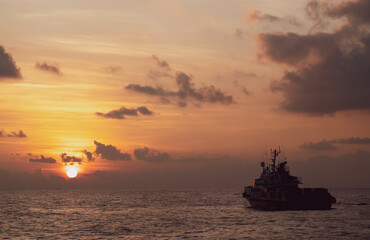 Fototapeta na wymiar The boat floats off the coast at sunset.