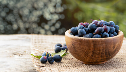 blackthorn berries in a wooden bowl on table with sacking and blurred background