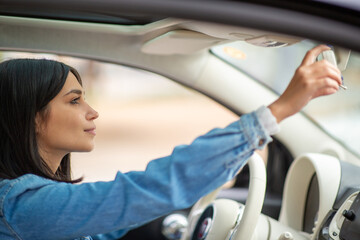 Fototapeta na wymiar Portrait young female driver adjusting rear view mirror