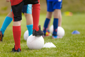 Soccer training drill for kids. Legs of football players attending soccer class. Children playing sports outdoor. School kids in soccer cleats kicking classic soccer balls - Powered by Adobe