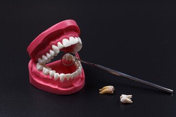 Stainless steel dental mirror and a layout of the human jaw on the black background.