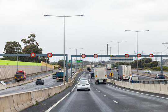 trucks and cars on busy multi lane road in Melbourne, Victoria with variable speed limit signs