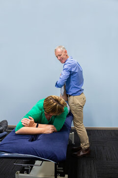 Physiotherapist working in professional clinic setting massaging leg of woman with injury