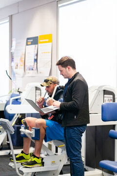 physio talking through results on laptop with client using exercise therapy equipment