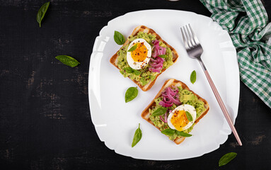 Healthy toast with mashed avocado, boiled eggs, spices and red onions. Delicious breakfast or snack. Top view