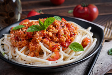 Spaghetti pasta and tomato sauce with chicken mince on a wooden background. Pasta bolognese.