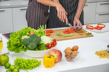 Obraz na płótnie Canvas Caucasian young couple in white kitchen cooking making preparing healthy food with vegetables wearing aprons.