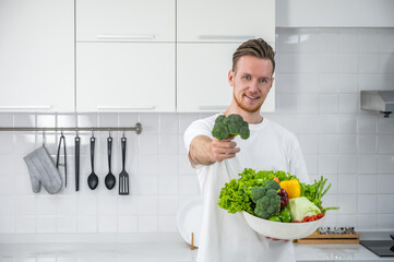 A caucasian man holding a bowl of mix vegetables and holding a broccoli. Vegetarian or vegan food healthy lifestyle concept.