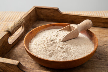 Psyllium husk flour powder on wood bowl and spoon indoors at home. Health benefits of Psyllium...