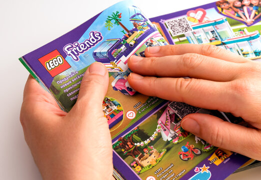 Tambov, Russian Federation - December 21, 2021 A woman browsing a Lego catalog on the page with Lego Friends sets