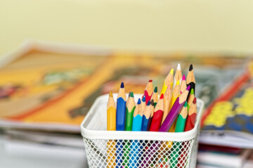 Colored pencils in a box against coloring books - 630683720