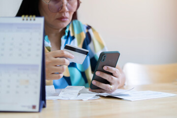 Close-up of hand asian businesswoman holding credit card and checking bank statement