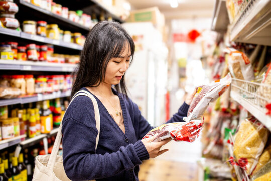 20-something Asian woman shopping buying groceries at a supermarket