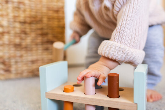 Toddler child playing with hammer pounding bench toy using hands to press blocks