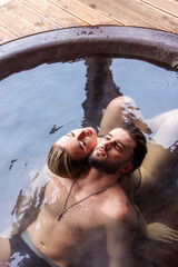 young couple hugging while sitting in a big tub of water