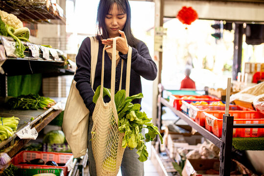 20-something Asian woman shopping buying groceries at a supermarket