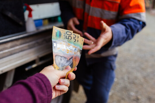 Persons hand passing over money for cash payment to handyman - paying in cash