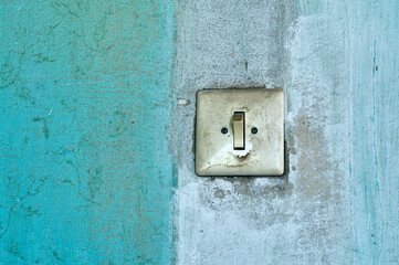 Old electric light switch, in an abandoned building, painted wall, paint faded from the sun and time