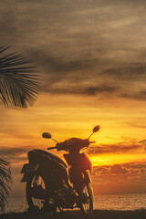 A motorbike on the background of an orange sunset by the sea. A serene holiday in Thailand, relaxation. Tourism and vacation travel in Asia