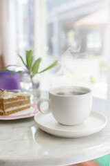 Coffee break. A mug of hot steaming coffee on the table, next to a cake. concept for a coffee shop