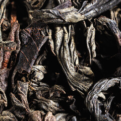Dried black tea leaves as background.