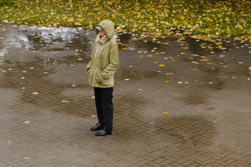 a woman in a pink jacket in black shoes and green trousers with a red bag in her hands walks down...