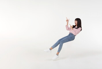 Young beautiful asian girl floating in mid-air relaxing and hand pointing finger to copy space with smile face and happy isolated on white background.