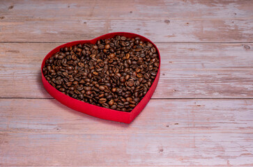 Coffee beans standing in heart shape on wooden background. Close-up and high resolution shot of coffee beans. There is a text field. Coffee and beverage banners and logos. Valentine's day concepts