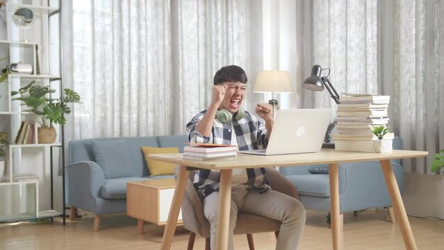 Asian Teenager Student Celebrating With Laptop Computer At Home, Teenage Boy Learning Online From Laptop
