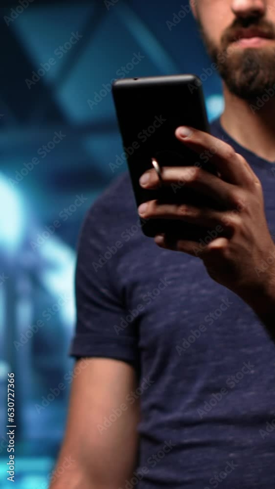 Poster vertical video man engineer working in server room using phone to check tech processing software for