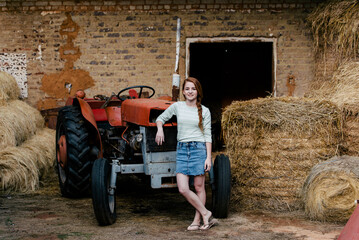 Farm girl farmer lady hay tractor farm work red hair Demin skirt shed barn