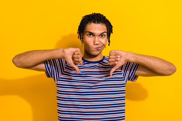 Portrait of disappointed man with piercing cornrows wear stylish t-shirt hold thumbs down dislike...