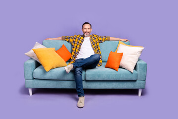 Photo of cheerful man boss wear plaid stylish clothes sit soft comfort sofa enjoy break pause...