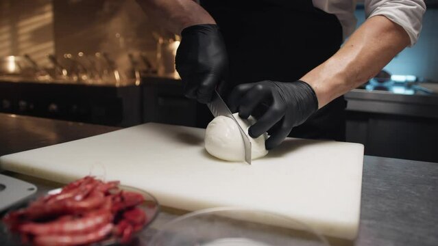 Chef cuts a DOP Campania mozzarella cheese on cutting board