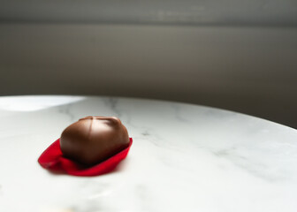 Single chocolate on a red rose petal