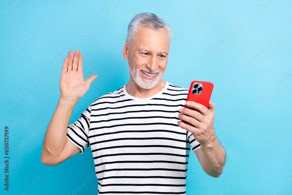 Sticker Photo portrait of nice elderly man wave hand video call hold gadget wear trendy striped outfit isolated on blue color background