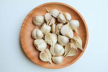 Garlic cloves or bulb on wooden plate, isolated on white background