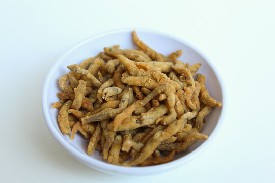 Teri crispy, is whitebait or baby anchovy fish or teri nasi in Indonesia, which fried with flour. In a small white bowl. Isolated on white background.
