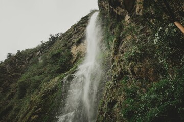 Waterfall cascading down the moss covered rocky cliff