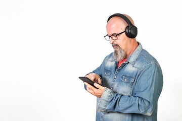 Caucasian bald middle-aged man with a goatee and glasses listening to music with headphones.