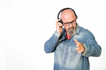 Caucasian bald middle-aged man with a goatee and glasses listening to music with headphones.