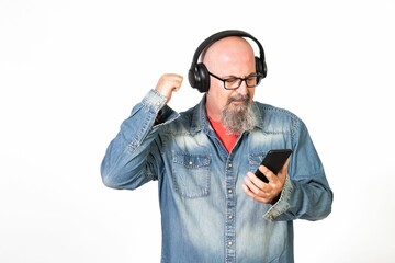 Caucasian bald middle-aged man with a goatee and glasses listening to music with headphones.