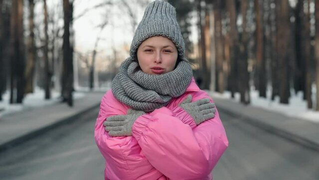 a young girl in and pink jacket freezes in a cold winter in a snowy forest